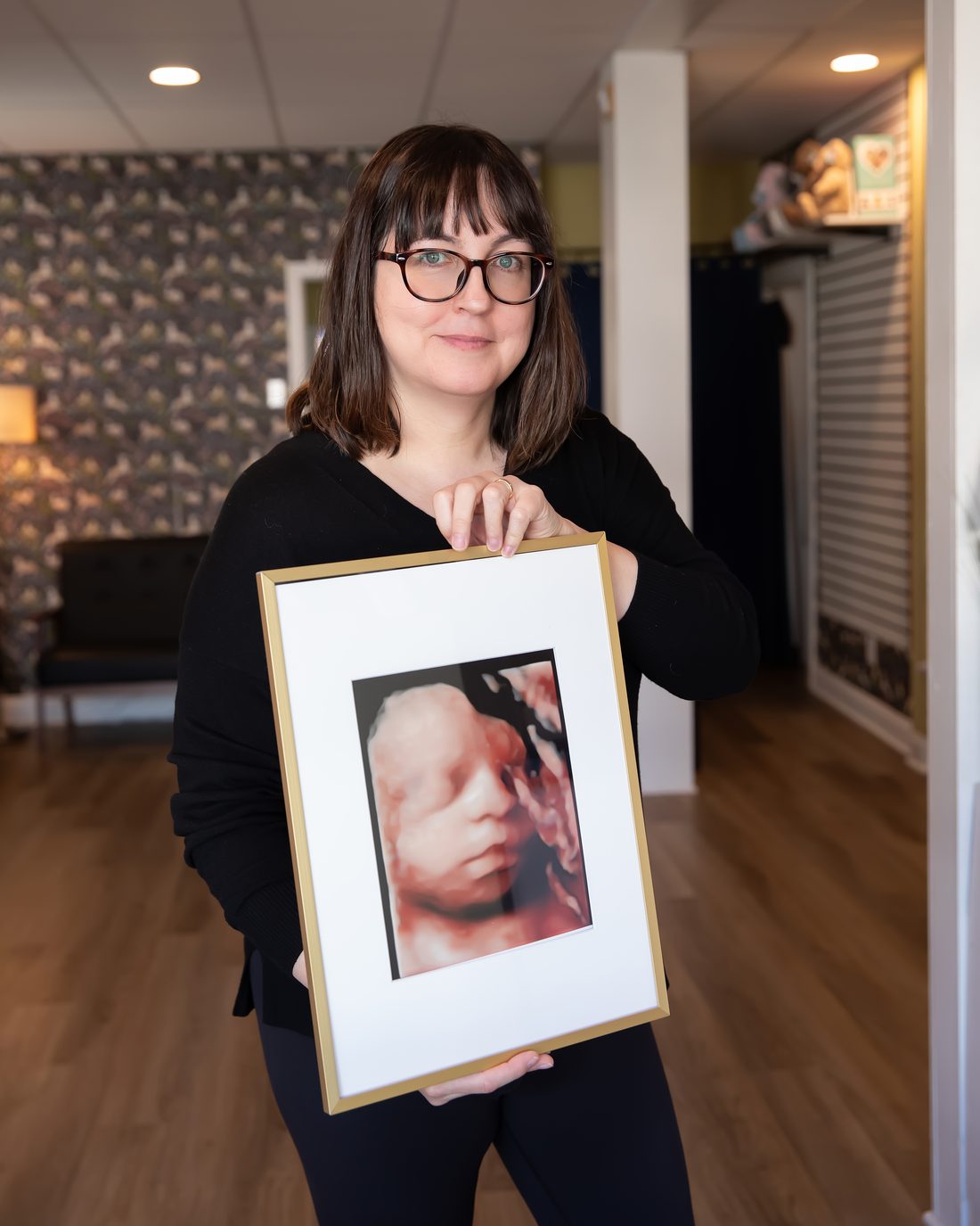 Happy mother holding a framed 3D ultrasound keepsake portrait from Wonder Time